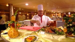 Chef carving meat at an MS Classic Blue Shadow IV 5* buffet table with decorative displays.