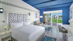 Hilton Hurghada room: double bed, seating area, and garden view through glass doors.