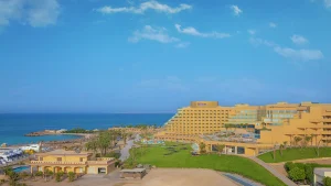 Hilton Hurghada hotel by the sea with grassy landscape and clear blue sky.