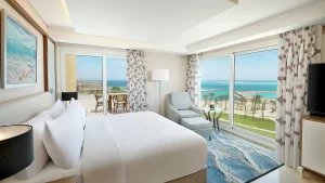 Hilton Hurghada room with a bed, armchair, balcony, and ocean view.