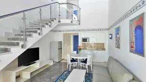 Modern Hilton Hurghada living room with kitchenette, staircase, and wall-mounted TV.