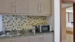 Modern Hilton Hurghada kitchenette with sink, kettle, microwave, and tiled backsplash.