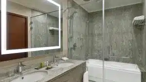 Modern Hilton Hurghada bathroom with double sink, illuminated mirror, and glass shower enclosure.