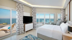 Hilton Hurghada room with ocean view, king bed, TV, and balcony seating area.