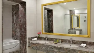 Hilton Hurghadas modern bathroom with double sinks, large mirror, and decorative stone.