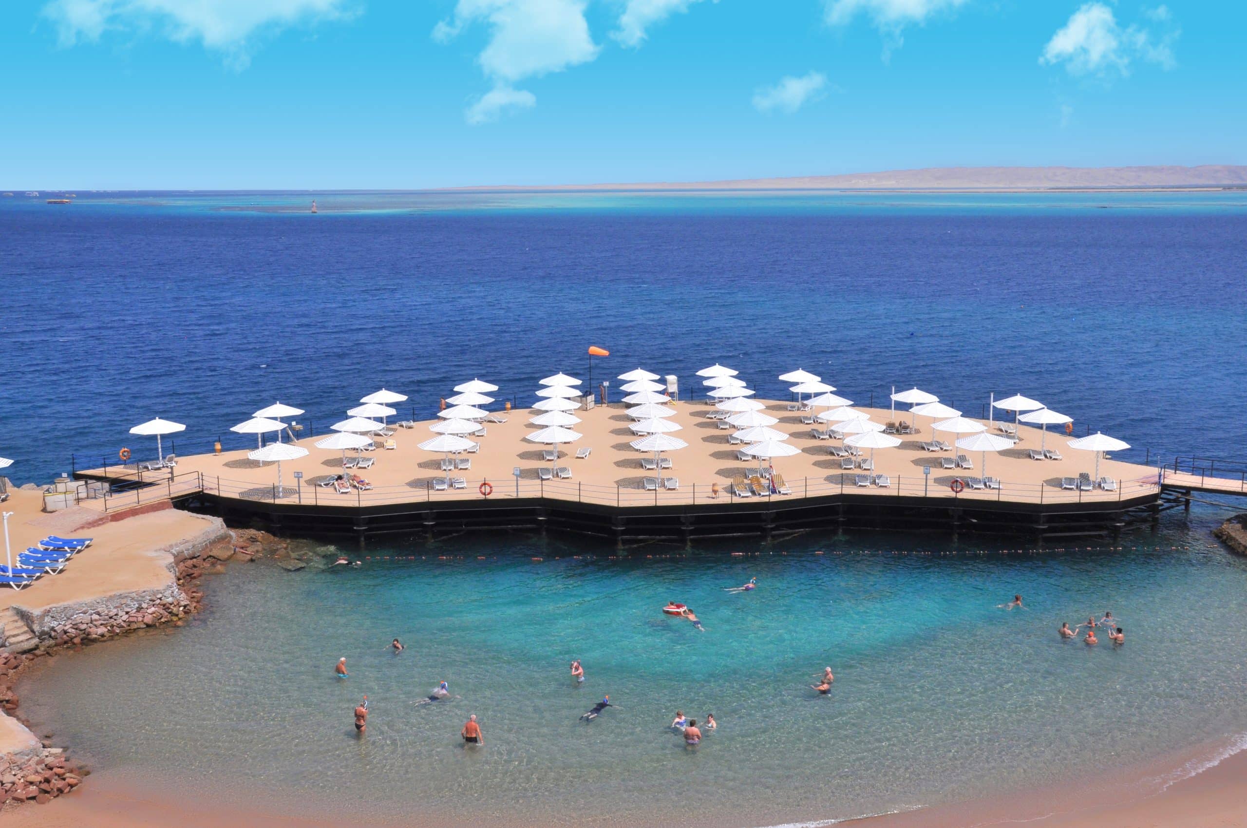 Sunrise Holidays Resort: a beach with wooden pier, white umbrellas, and clear blue water.