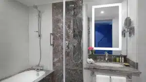 Modern Hilton Hurghada bathroom with a bathtub, shower, vanity mirror, and sink.