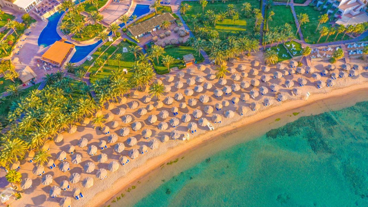 Aerial view of Fort Arabesque Resorts beach with straw umbrellas and turquoise water.
