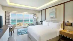 Hilton Hurghada room with a large bed, seating area, and ocean view through a wide window.