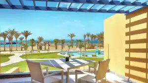 Hilton Hurghada patio: chairs, palm trees, pool, and sea under a blue pergola.