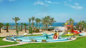 Colorful water playground at Hilton Hurghada with slides, sandy beach, and palm trees.