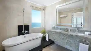 Modern bathroom at Hilton Hurghada with a bathtub, dual sinks, mirror, and ocean view.