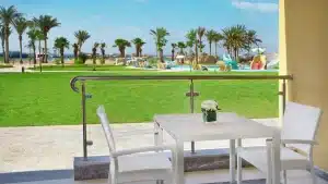 Hilton Hurghada patio with white furniture overlooking a lawn, pool, and palm trees.