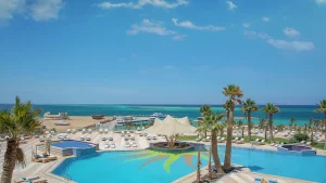 Beachfront pool at Hilton Hurghada with palm trees, lounge chairs, and ocean view.