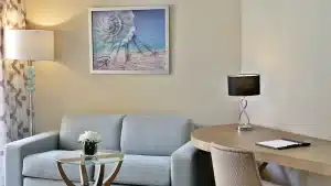 Modern Hilton Hurghada room with a sofa, art, and desk lamp beside a round table and chair.