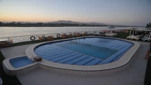 MS Classic Blue Shadow IV 5*: Rooftop pool with lounge chairs, overlooking a calm river at sunset.
