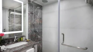 Modern bathroom at Hilton Hurghada with a glass shower, marble countertop, and illuminated mirror.