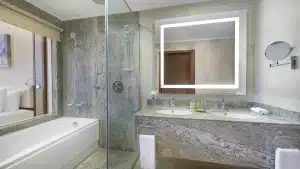 Modern Hilton Hurghada bathroom with dual sinks, bathtub, and glass shower.