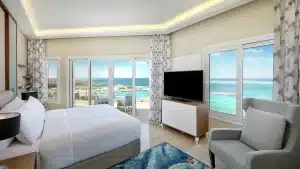 Hilton Hurghada room: large bed, armchair, TV, ocean view through big windows.