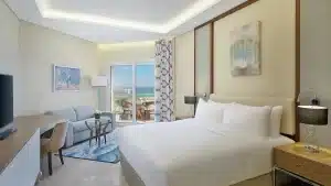 Hilton Hurghada room with a large bed, seating area, and balcony overlooking the ocean.