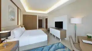 Hilton Hurghada room with modern decor: bed, TV, desk, and lamp on a blue rug.