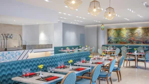 Hilton Hurghadas modern restaurant features blue seating, set tables, lights, and art.