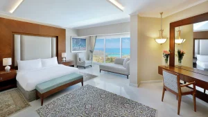 Hilton Hurghada offers a spacious room with sea view, modern decor, large bed, and sitting area.