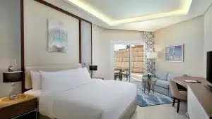Modern Hilton Hurghada room with double bed, sofa, desk, and terrace view.