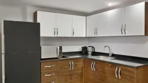 Modern kitchen with white cabinets, wooden cupboards, fridge, microwave at Hilton Hurghada.