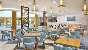 Modern Hilton Hurghada dining area with wooden tables, patterned chairs, and decorative lights.