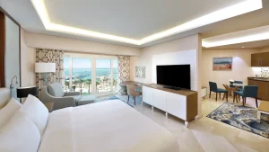 Modern Hilton Hurghada room with a bed, seating area, TV, and ocean view through large windows.