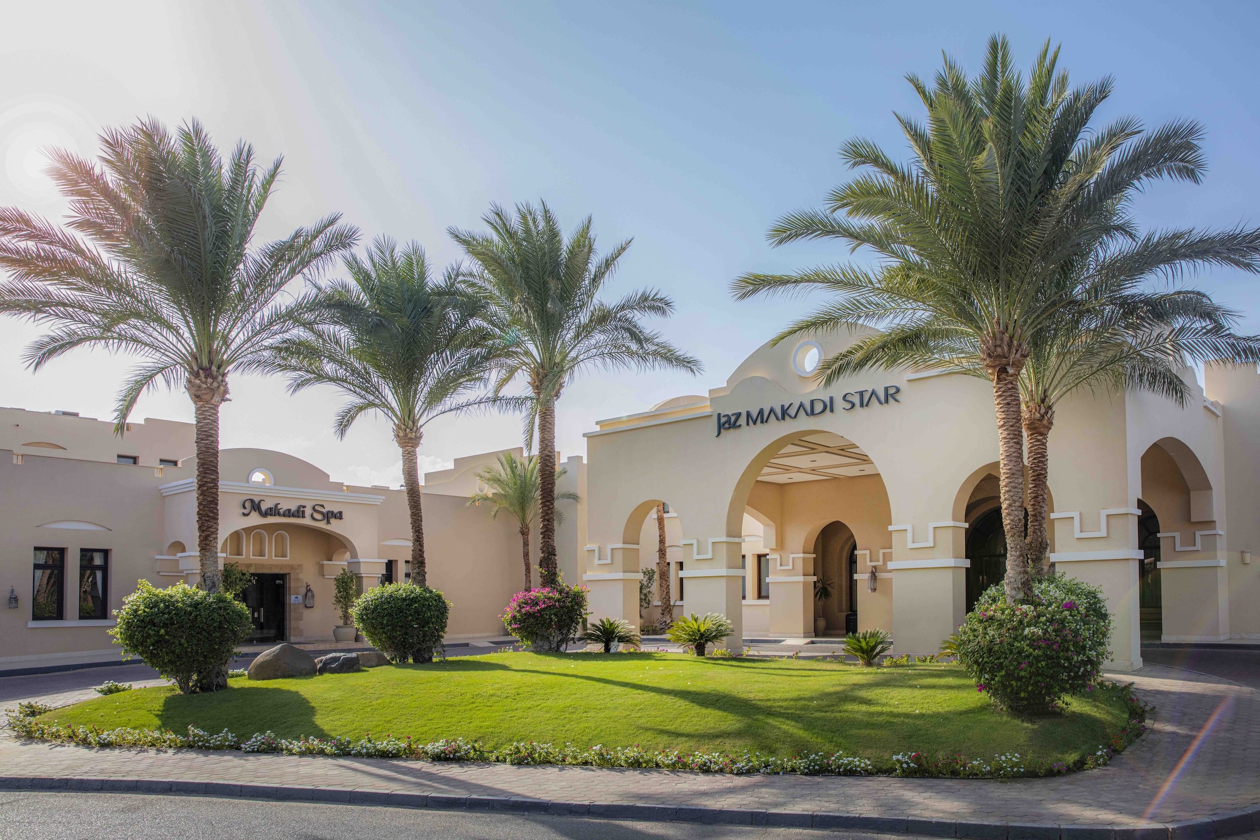 Jaz Makadi Star & Spa: White building, palm trees, and a lush green lawn.