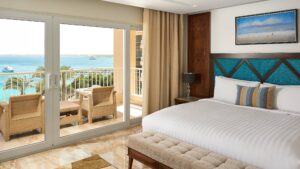 Hurghada Marriott room with a bed, balcony, chairs, and ocean view.
