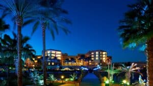 Hurghada Marriott Beach Resort glowing at night, with palm trees and a pathway in the foreground.