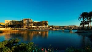 Hurghada Marriott Beach Resort by a calm lake, surrounded by palm trees under a clear blue sky.