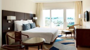 A room at Hurghada Marriott with chairs, a bed, and a balcony overlooking the sea.