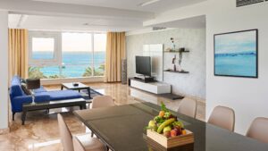 Modern living room at Hurghada Marriott Beach Resort, sea view, blue sofa, TV, and fruit centerpiece.