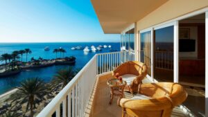 Balcony view at Hurghada Marriott Beach Resort with ocean, boats, palms, and wicker chairs.