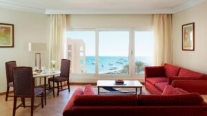 Living room with red sofas, dining table, and sea view like at Hurghada Marriott Beach Resort.