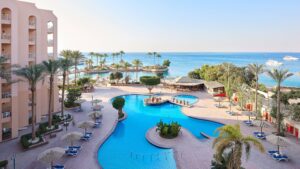 A resort pool at Hurghada Marriott with palm trees overlooking the ocean and distant boats.