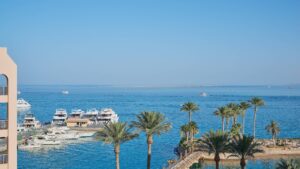 Hurghada Marriott Beach Resort marina with docked boats and palm trees by clear blue sea.