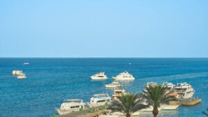 View of a harbor by Hurghada Marriott Beach Resort, boats sailing on a clear sea under the sunny sky.