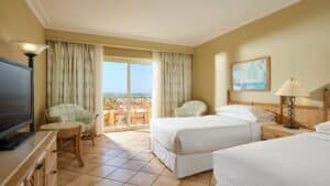 Sheraton Soma Bay room with two beds, a TV, and balcony sea view.