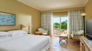 Sheraton Soma Bay room with a cozy bed, TV, chairs, and lush green views.