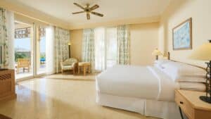 A bright Sheraton Soma Bay room with a bed, chair, table, and patio access.