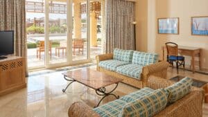 Sheraton Soma Bays spacious living room with wicker furniture, TV, desk, and patio views.