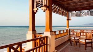 Wooden terrace at Sheraton Soma Bay with chairs, patterned railing, and a calm sea view.