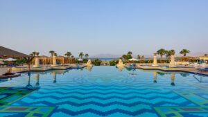 Luxurious Sheraton Soma Bay pool with geometric patterns, palm trees, and a distant sea view.