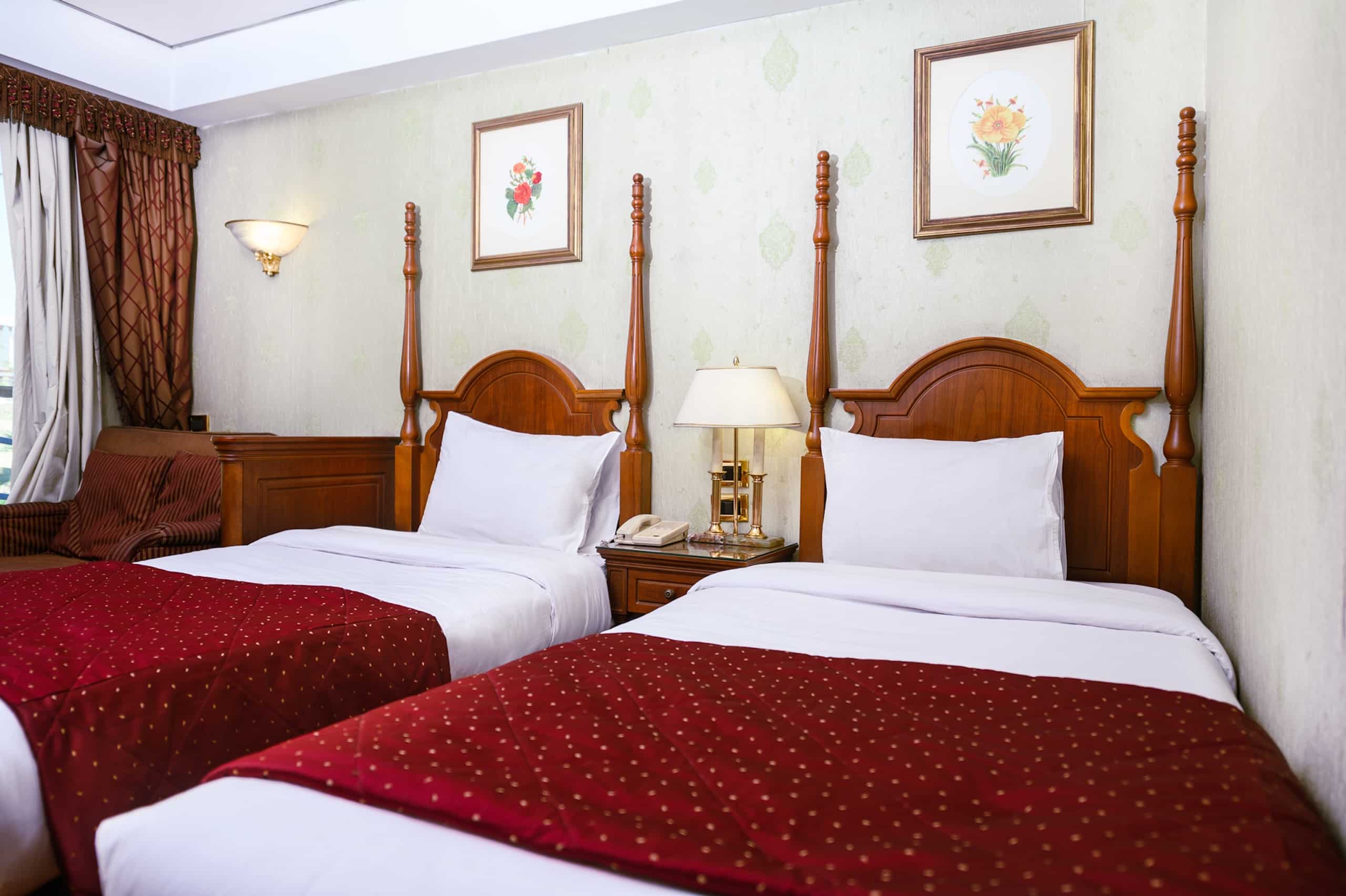 Twin beds in a room aboard the MS Royal Princess, with red bedspreads and floral art on the walls.
