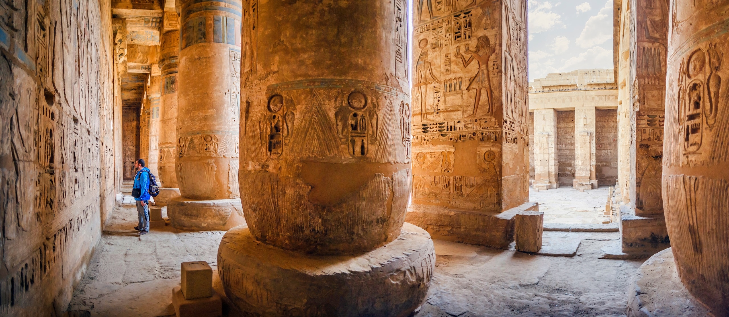 The tourist considers the hieroglyphs on the walls of the temple of Medinet Habu. Egypt, Luxor. The Mortuary Temple of Ramesses III at Medinet Habu is an important New Kingdom period structure in the West Bank of Luxor in Egypt